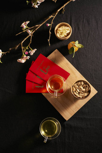 农历新年食物和饮料在深色的木桌上，樱花盛开的枝条