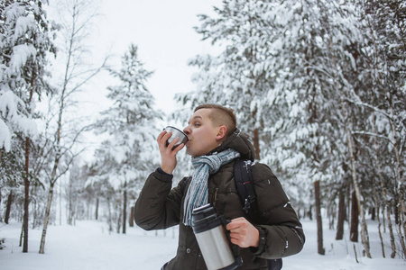 在雪针叶林里, 带着热水瓶的时尚男人