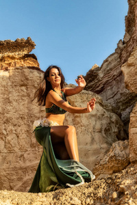 少女穿着绿色连衣裙舞动着著名的肚皮舞，在神话中的纳米贝沙漠峡谷的空间里。非洲。安哥拉。