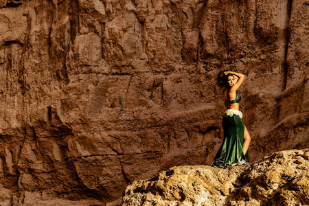 年轻的女孩穿着绿色的裙子，在纳米贝沙漠峡谷的神话空间里跳着著名的肚皮舞。 非洲。 安哥拉。