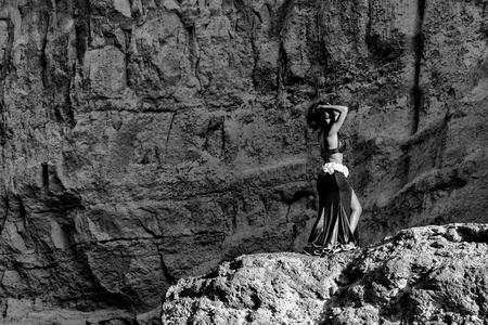 年轻的女孩穿着绿色的裙子，在纳米贝沙漠峡谷的神话空间里跳着著名的肚皮舞。 非洲。 安哥拉。 BW版本。