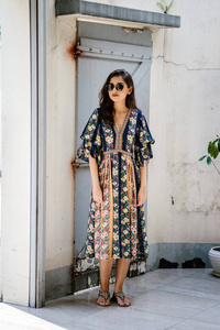一位身材高大优雅美丽的印度亚裔女性，穿着夏装，戴着太阳镜，白天在小巷的一条街上摆姿势着