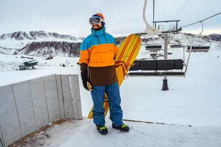 滑雪场。 一个手里拿着滑雪板的人正站在椅子上。 吉尔吉斯斯坦山区