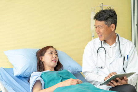 亚洲高级医生坐在病床上，与女性患者讨论选择性焦点