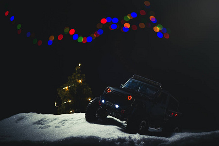 无线电控制的汽车在雪中在夜间灯光照耀。 圣诞娱乐礼物RC车。