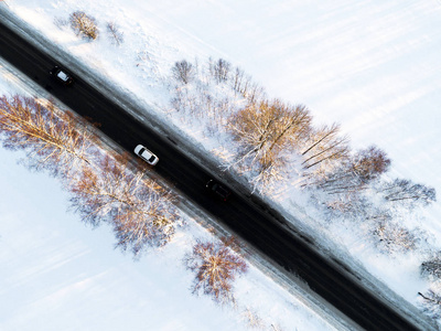 森林冬季道路上汽车的鸟瞰图。 冬季景观乡村。 空中摄影雪林与一辆汽车在路上。 用无人机从上面捕获。 空中照片。 汽车在运动