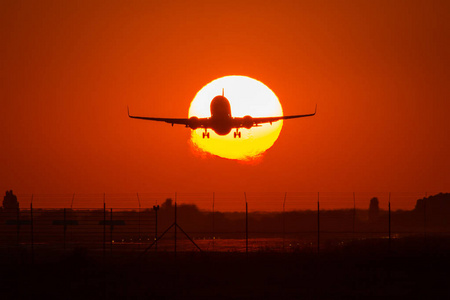空中飞机在太阳上空的轮廓，背景是美丽的红云