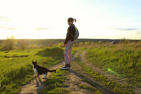 年轻的少女和她的燕尾服猫散步。 主人和宠物在户外。 儿童动物宠物旅行的概念。