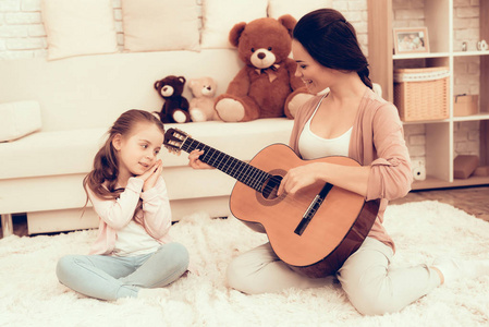 孩子们的家庭游戏。 在家休息。 儿童发展。 妈妈和女儿玩。 穿睡衣的快乐妈妈和孩子。 女人和女儿。 弹吉他。 弹吉他的女人。 妈