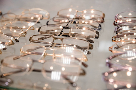 一排排豪华的眼镜在眼镜店。时尚光学眼镜的侧视图, 挂在透明的设置与其他眼镜。视觉改善和保护。医疗