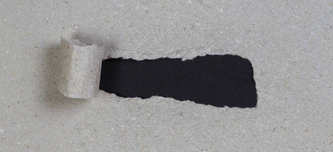 棕色包裹纸撕破, 以显示黑色背景与复制空间