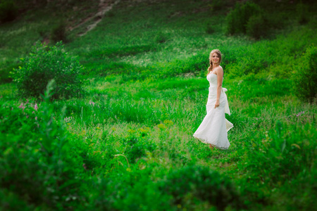 美丽的新娘在山和草的背景下。