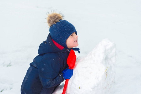 孩子用铲子堆雪人, 在雪地里玩