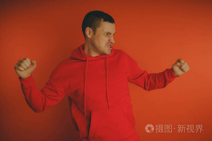 在橙色背景上摆姿势的疯狂而有魅力的家伙.穿红色运动