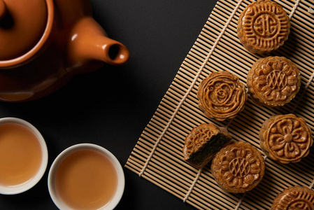 传统月饼茶壶和竹桌垫子上的杯子的俯视图
