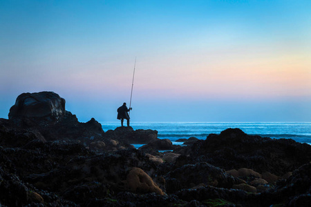 一个渔民的剪影, 看着在黄昏的海边和