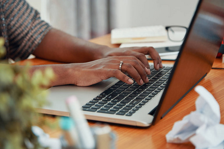 现代黑人女商人在办公室的桌子上用手提电脑和键盘打字