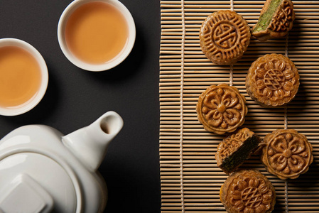 传统月饼茶壶和竹桌垫子上的杯子的俯视图