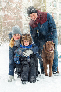 冬天和狗在一起的幸福家庭。 在下雪的冬天，美丽的浪漫气氛。 关系的概念。