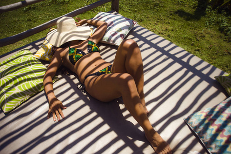 年轻的美女，穿着比基尼，冰镇和放松，躺在户外床上，晒太阳，享受暑假，在热带岛屿背景下度假，旅行，吸引人的身体概念。