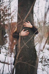 冬天，孤独的女人在森林里抱着树。