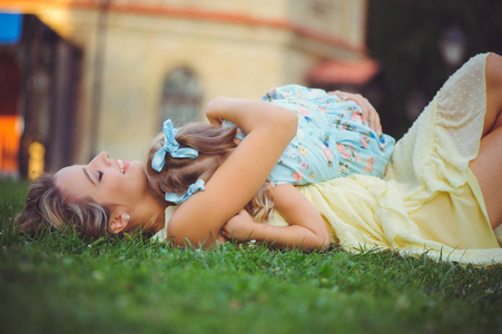 有孩子的美女。 美丽快乐的年轻女子正在草地上享受乐趣，高兴地拥抱着女儿的形象