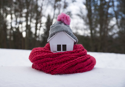 冬季住宅供暖系统的概念和寒冷的雪天，带针织帽的房子模型