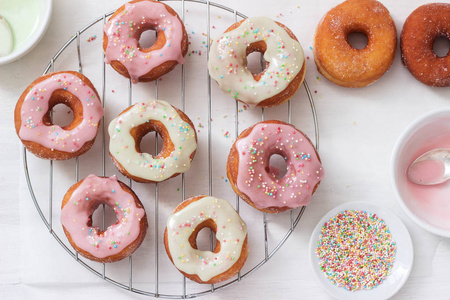 自制甜甜圈装饰彩色糖霜和彩色糖在一个轻的背景。 选择性聚焦。