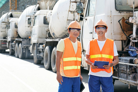 欢快的越南建筑工程师站在建筑工地的水泥卡车旁