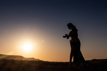 女人跳着著名的阿拉伯肚皮舞。 在纳米比亚干旱的沙漠平原上日落。 非洲。 安哥拉。