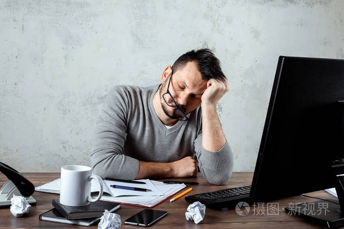 一个男人,一个睡在办公室桌子旁的人.