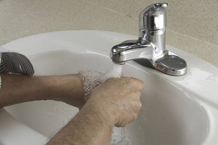 在卫生间洗手池里洗手的人图片