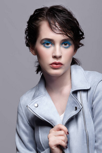 穿蓝色夹克的女性肖像。 有着不寻常的美妆和湿发的女人。 女孩有完美的皮肤，绿色开心果，眼睛和蓝色的阴影组成。