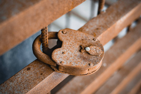 在生锈的铁栅栏上，在水和空气的影响下，在露天关闭一个旧生锈的锁的金属腐蚀。 老式物品