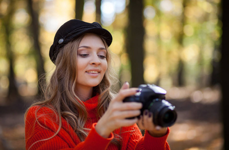 一位年轻女子在公园里玩相机拍照