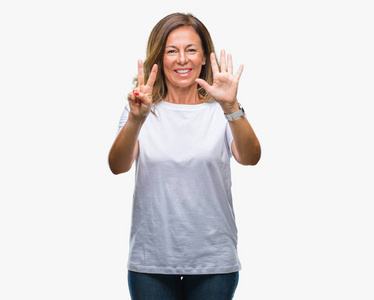 中年老年西班牙裔妇女在孤立的背景下，用手指7号，微笑着自信和快乐。