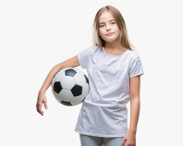 年轻漂亮的女孩抱着足球球在孤立的背景上，自信的表情在聪明的脸上，严肃的思考