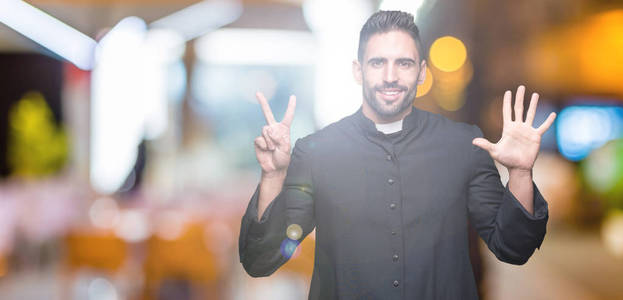年轻的基督教牧师在孤立的背景显示和指向7号手指，同时微笑自信和快乐。