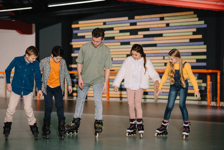 向细心的儿童展示滑冰基本技术的年轻教练