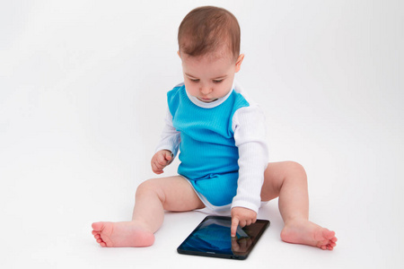 可爱的婴儿蹒跚学步的孩子坐在白色背景上玩平板电脑