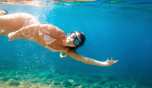 美丽的女人水下浮潜在清澈的热带水中