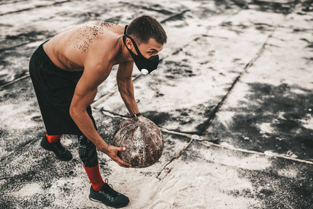 运动员肌肉男做运动与药球面具在混凝土背景户外与复制空间为您的广告。 白种人赤膊运动员做运动