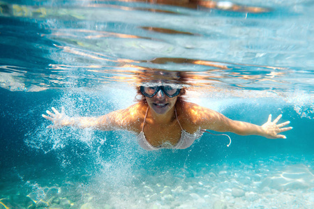 带着面具的微笑女人在清澈的热带水中潜水