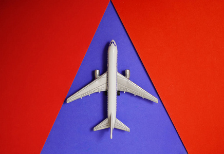 红色和蓝色纸背景上的金属玩具飞机。 旅行和交通理念。