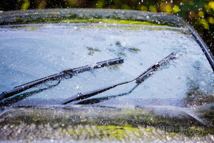 带有雨滴和无框雨刷叶片特写的汽车挡风玻璃