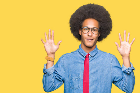 年轻的非裔美国商人带着非洲头发，戴着眼镜和红色领带，用十号手指展示和指着，同时微笑着自信和快乐。