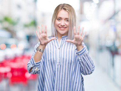 年轻的金发女人在孤立的背景上显示和指着数字10，同时微笑自信和快乐。