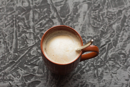 灰色背景棕色杯子里的热卡布奇诺咖啡