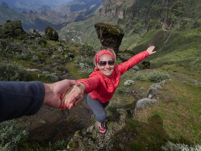 夏季高山地带的年轻女子游客男子帮助她攀登