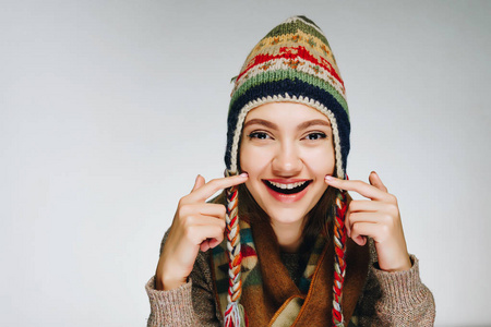 年轻的开朗的妇女在斯堪的纳维亚温暖的帽子和围巾在白色背景显示健康的皮肤